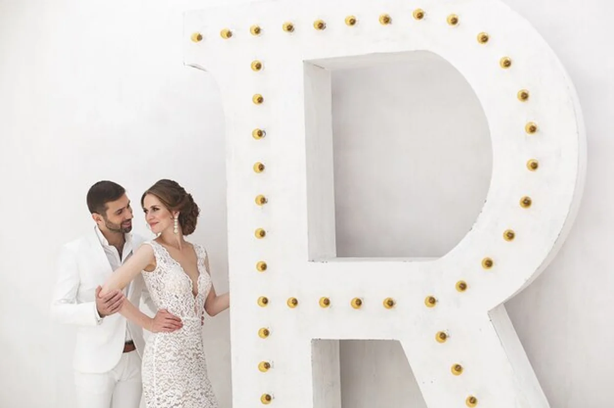 Para młoda pozująca w eleganckim studiu ślubnym. Biała sukienka, garnitur, szczęście, sofa, żyrandol, drzwi