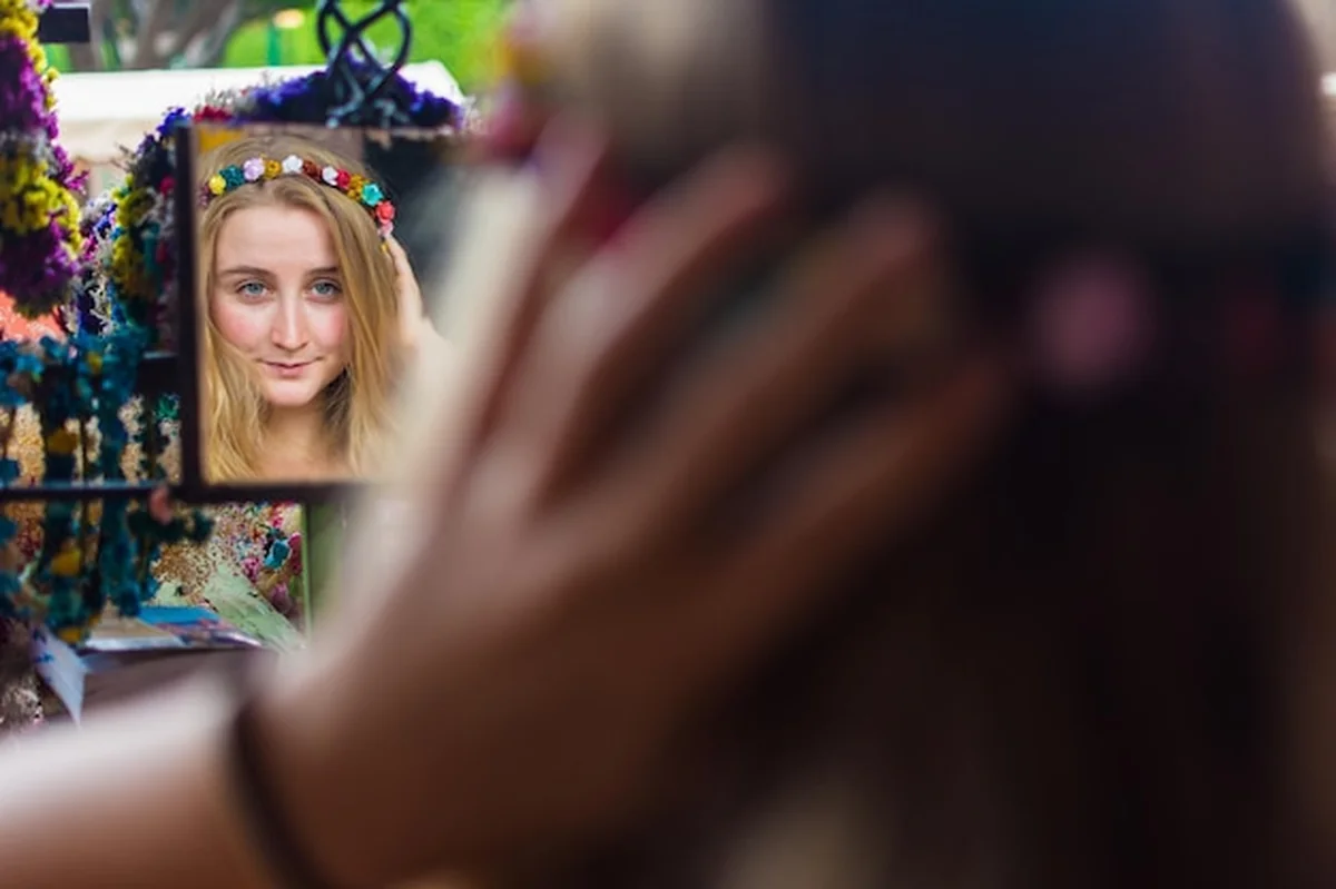 Młoda kobieta w tiarze odzwierciedlająca się w lustrze