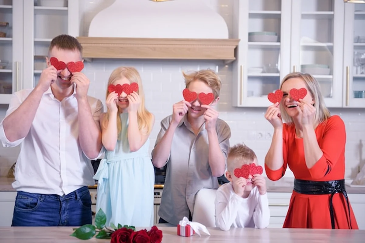 Szczęśliwa pełna rodzina trzyma czerwone serca w kuchni