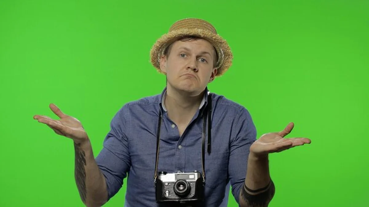 Młody turystyczny fotograf wzruszający ramionami przed tłem Chroma key