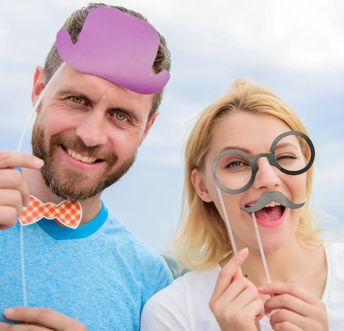 Para pozuje z rekwizytami przed fotobudką