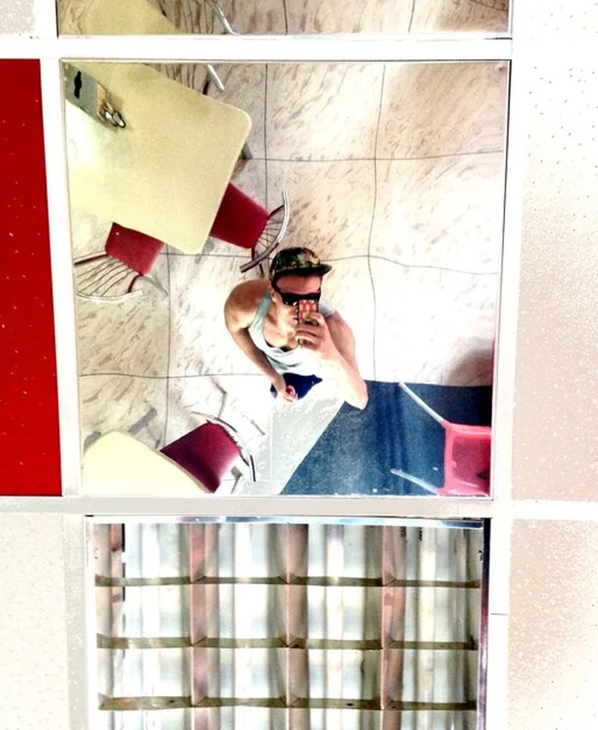 Mężczyzna odbijający się od lustra podczas robienia selfie w restauracji