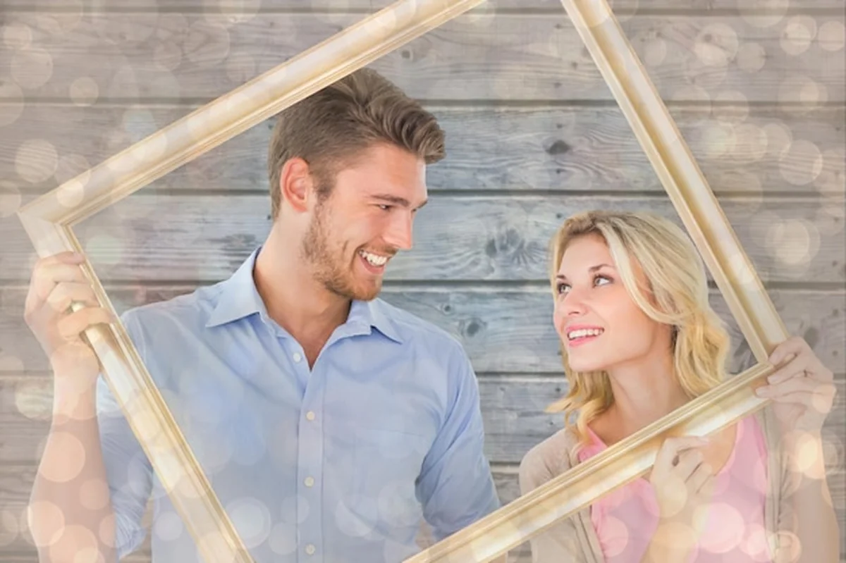 Młoda para trzyma ramkę na zdjęcia przed wzorem projektowym