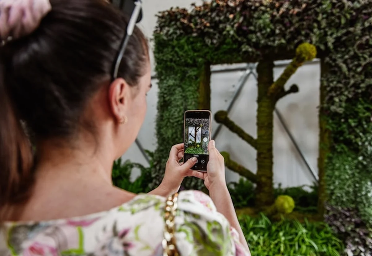 Kobieta robiąca zdjęcia roślinom w ogrodzie botanicznym