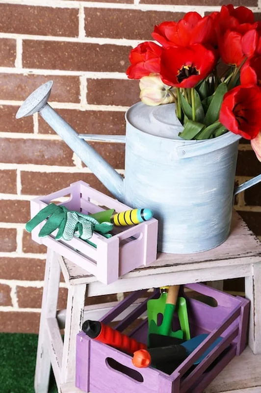 Kompozycja kolorowych tulipanów w konewce i sprzęt do ogrodnictwa na jasnym tle