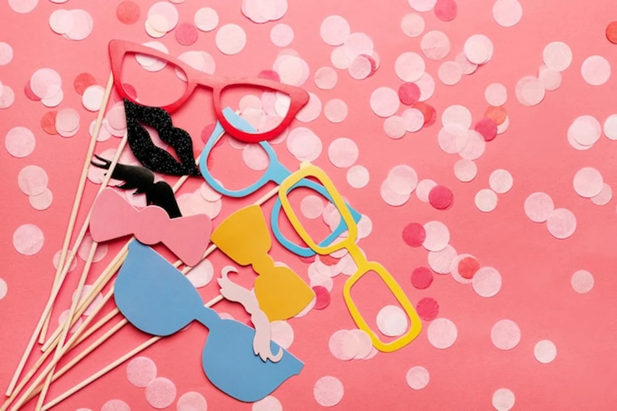 Fotobudka z rekwizytami: okulary, wąsy, usta na różowym tle